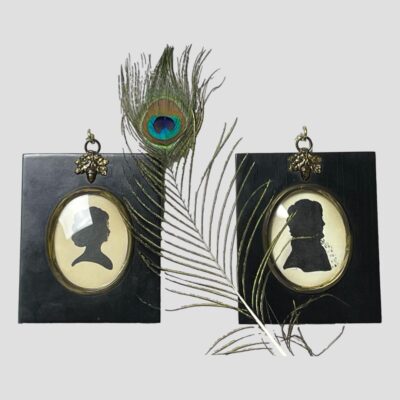 Main photo of the 2 portraits displayed side by side with a single peacock feather between the 2. Both silhouette profiles are facing to the right.