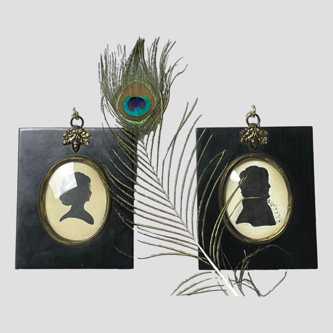 Main photo of the 2 portraits displayed side by side with a single peacock feather between the 2. Both silhouette profiles are facing to the right.