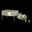 Main photo of jewellery box shown at eye level and closed with the front facing slightly to the left. Two small silver knobs are visible to the left and right of the frontage with the thin silver legs also visible. There is a sprig of small white orchids to the right.