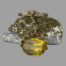 Main photo of fob shown with the pin and chain resting on top of a small natural rock and the large citrine stone in the foreground placed in front of the rock. The citrine has a lovely dark lemon colour. The gold appears to be both yellow and rose gold in 9 karat.