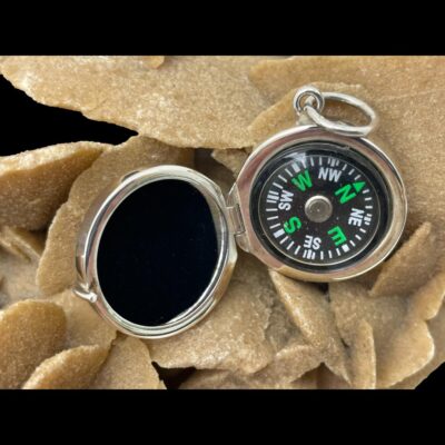 A close up of the open compass now displayed on top of the desert rose.
