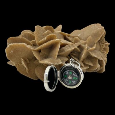 Main photo of compass shown open and standing upright on its own in front of a rock of natural desert sand rose.
